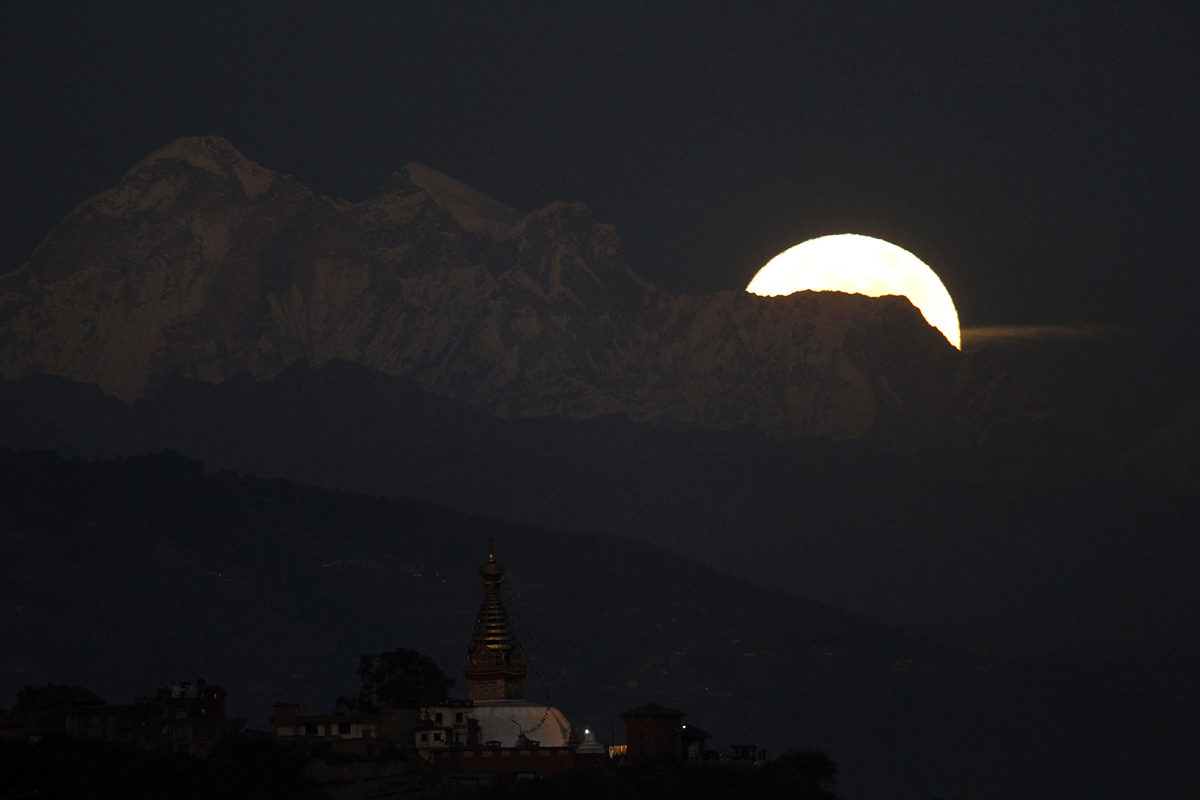 The moon rises behind the Dorje Lakpa Mountain as Swayambhunath stupa is seen in forground in Kathmandu, Nepal, Monday, Nov. 14, 2016. The brightest moon in almost 69 years lights up the sky this week in a treat for star watchers around the globe. The phenomenon known as the supermoon will reach its most luminescent in North America before dawn on Monday. (AP Photo/Niranjan Shrestha)