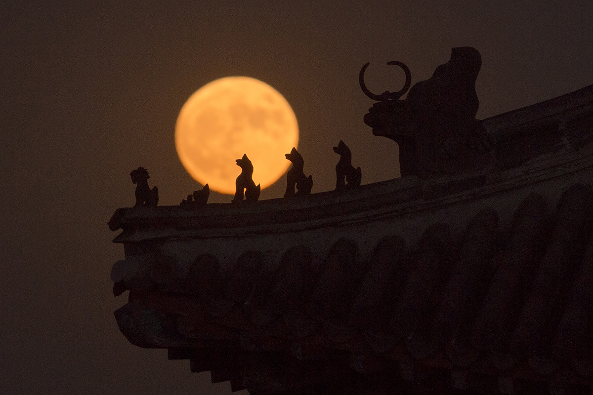 A "supermoon" rises behind small sculptures standing on the roof of a tower in the Forbidden City in Beijing on November 14, 2016. Skygazers headed to high-rise buildings, ancient forts and beaches on November 14 to witness the closest "supermoon" to Earth in almost seven decades, hoping for dramatic photos and spectacular surf. The moon will be the closest to Earth since 1948 at a distance of 356,509 kilometres (221,524 miles), creating what NASA described as "an extra-supermoon". / AFP / NICOLAS ASFOURI (Photo credit should read NICOLAS ASFOURI/AFP/Getty Images)