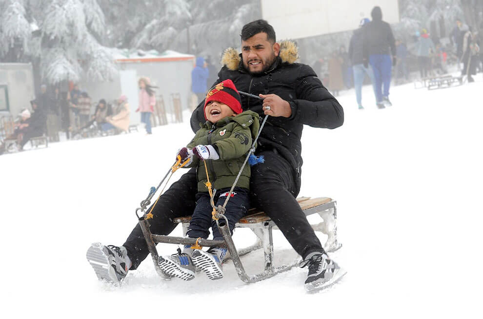 مردم از سورتمه سواری به پایین تپه در مرکز اسکی در ارتفاعات شهر چریا، در استان تبسا، الجزایر، در ۲۳ ژانویه ۲۰۲۳ لذت می‌برند.