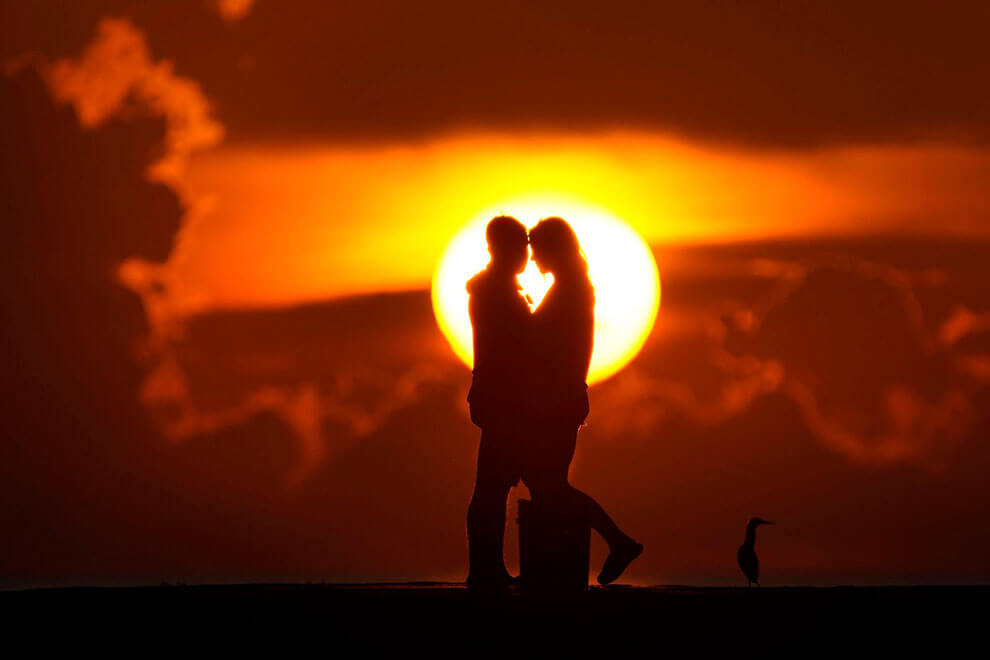 یک زوج طلوع خورشید را بر فراز اقیانوس اطلس در بال هاربر فلوریدا در ۲۸ ژوئن ۲۰۲۳ تماشا می‌کنند.