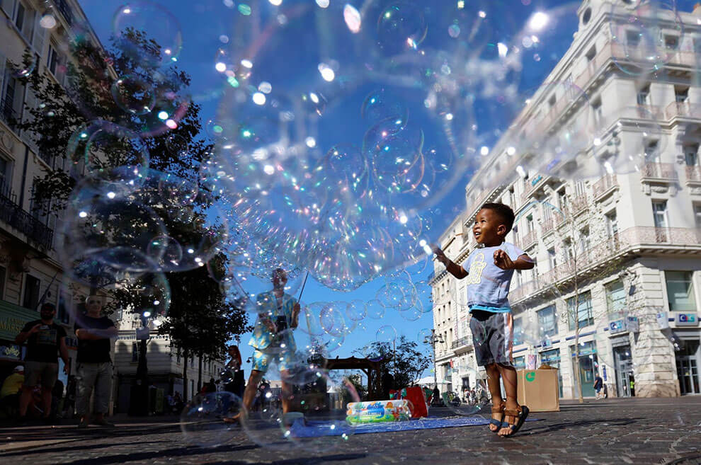 کودکی در ۹ سپتامبر ۲۰۲۳ در بندر قدیمی مارسی، فرانسه با حباب‌های یک مجری خیابانی بازی می‌کند.